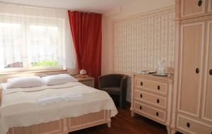 a bedroom with a bed and a dresser and a window at Ośrodek Wczasowy GAMA in Rewal