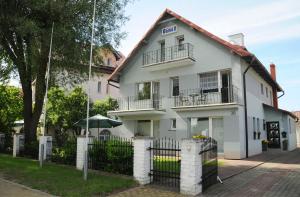a white house with a fence in front of it at Ośrodek Wczasowy GAMA in Rewal
