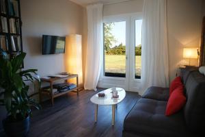 sala de estar con sofá, mesa y ventana en La Dunette, en Penmarch