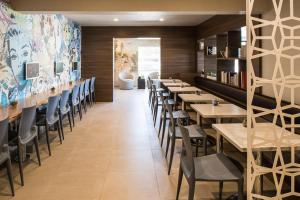 a restaurant with rows of tables and chairs at The Dylan Hotel at SFO in Millbrae