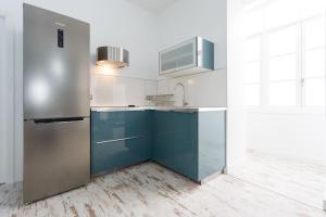 カディスにあるLa Perla de La Caletaのキッチン(青いキャビネット、ステンレス製の冷蔵庫付)