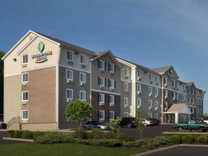 an apartment building with cars parked in a parking lot at WoodSpring Suites Kansas City Mission in Merriam