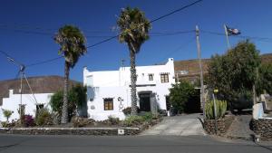 een wit huis met palmbomen ervoor bij Finca Lanzarosy in Guatiza