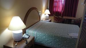 a hotel room with a bed with a lamp and a clock at Brasao Palace Hotel in Presidente Prudente