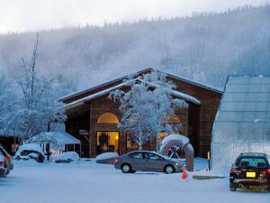 a snow covered building with cars parked in front of it at Chena Hot Springs Resort in Chena Hot Springs