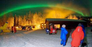 a group of people standing in front of a cabin under the aurora at Chena Hot Springs Resort in Chena Hot Springs
