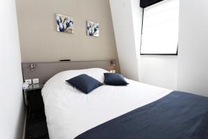 1 dormitorio con 1 cama blanca y 2 almohadas azules en Hôtel De L'Ill, en Estrasburgo