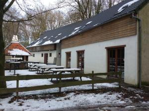 a building with tables and a fence in the snow at Le Domaine Appartements in Bilstain