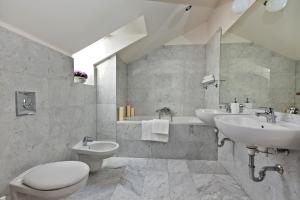 a white bathroom with two sinks and a toilet at Royal Prague City Apartments in Prague