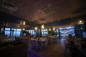 un restaurant avec des tables et des chaises et une personne assise dans une pièce dans l'établissement Hotel Agapi Mamaia, à Mamaia