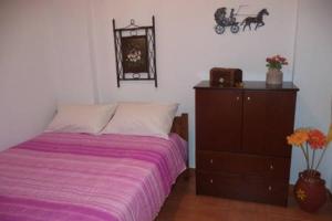 a bedroom with a bed and a dresser with a purple blanket at Kavousi Traditional Home in Falasarna