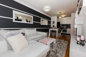 a living room with a white couch and a kitchen at Ella Apartman Zagreb in Zagreb