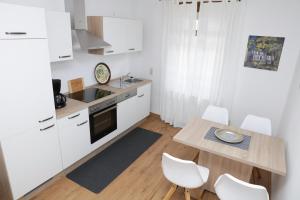 ツェルティンゲン・ラハティグにあるGeorgs Ferienhausの白いキャビネット、テーブルと椅子付きのキッチンが備わります。