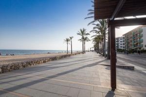 a sidewalk next to a beach with palm trees at Calafell Apartment 4 in Calafell