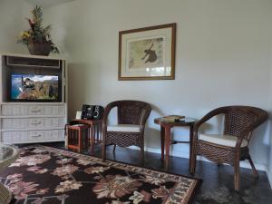 a living room with two chairs and a tv at Hale Pua Villa - Hibiscus Suite in Koloa