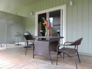 a table with chairs and a vase with flowers on it at Hale Pua Villa - Hibiscus Suite in Koloa