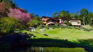 una casa en una colina junto a un cuerpo de agua en Eco Resort Nagual, en São Pedro da Serra