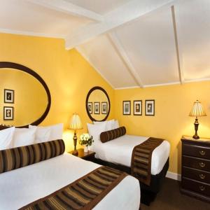 Habitación de hotel con 2 camas y espejo en Monterey Peninsula Inn, en Pacific Grove