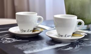 two white cups and saucers on a table at One Love Central Studio II in Bucharest