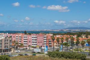 a view of a city with pink buildings and the ocean at Beach Houses in Costa da Caparica