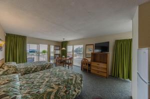 a hotel room with two beds and a desk and a television at Attache Motel in Wildwood Crest