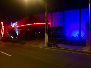 a building with a neon sign on a street at night at Motel Fuego (Adults Only) in Betim