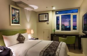 Schlafzimmer mit einem Bett, einem Schreibtisch und einem Fenster in der Unterkunft The Exchange Regency Residence Hotel Managed by HII in Manila