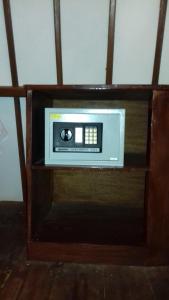 a microwave in a wooden shelf in a room at We'Be Cottages in Gili Meno