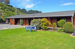 una mesa de picnic azul en el patio de una casa en Leith Valley Holiday Park and Motels, en Dunedin