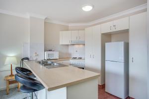 a kitchen with a sink and a white refrigerator at Paradise Isles in Gold Coast
