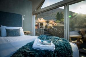 a bedroom with a bed with a towel and a window at SkyScape in Twizel