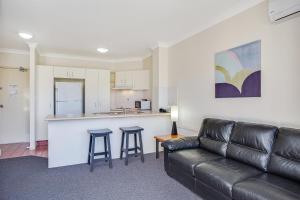a living room with a couch and a kitchen at Paradise Isles in Gold Coast