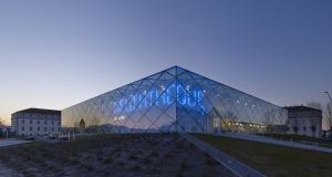 a large glass building with a pyramid facade at dusk at Hotel de la Gare in Mont-de-Marsan