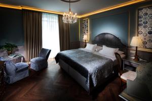 a bedroom with a bed and a chair and a chandelier at Hotel Bristol Salzburg in Salzburg