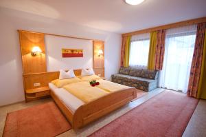 a bedroom with a large bed and a chair at Apart-Pension Wasserfall in Neustift im Stubaital