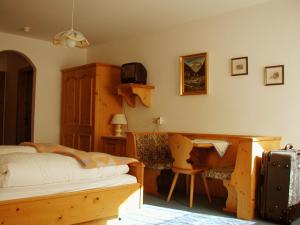 a bedroom with a bed and a desk and a chair at Hotel Stolz in Matrei am Brenner
