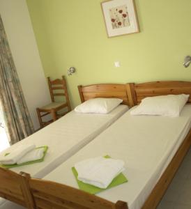 two twin beds in a room with a chair at Nikolaki Rooms in Porto Rafti