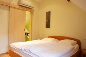 a bedroom with a bed with white sheets at Le Grenier Des Arômes Au Domaine Wittmann in Mittelbergheim