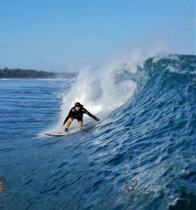 Un uomo che cavalca un'onda su una tavola da surf nell'oceano di Sumatra Surf Resort a Biha