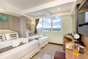 two beds in a hotel room with a large window at RoomQuest Suvarnabhumi Airport Romklao Soi 6 in Lat Krabang