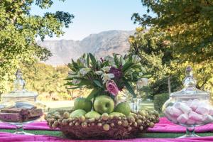 a table with a bowl of fruit and a vase of flowers at Le Manoir de Brendel in Franschhoek