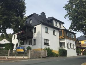 ein großes weißes Haus mit schwarzem Dach in der Unterkunft Ferienwohnung "Am Eisenbühl" in Berg