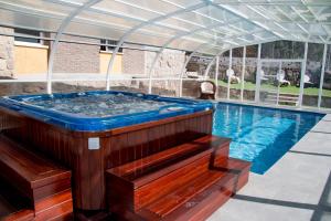 a hot tub in a greenhouse next to a swimming pool at Casa Rural Collarubio in Collado Mediano