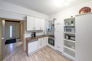 Ennshäusl by Schladming-Appartements في سخلادميخ: مطبخ بدولاب بيضاء وأرضية خشبية