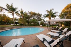 a swimming pool with lounge chairs and an umbrella at Le Manoir de Brendel in Franschhoek