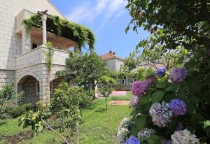 a garden with purple flowers in front of a house at Marija Rooms in Dubrovnik