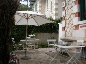 uma mesa e cadeiras com um guarda-sol num pátio em Villa Frivole em Saint-Palais-sur-Mer