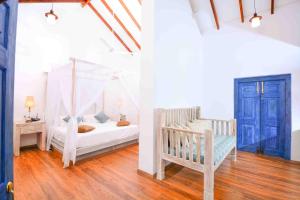 - une chambre avec un lit à baldaquin et un lit bébé dans l'établissement Handun Villas, à Talalla South