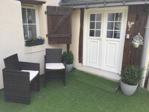 a patio with two chairs and a door and some plants at la bonbonniere in Saunay