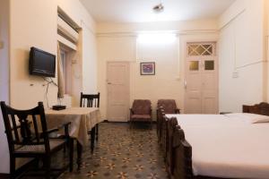 um quarto com duas camas, uma mesa e cadeiras em Bed and Breakfast at Colaba em Mumbai